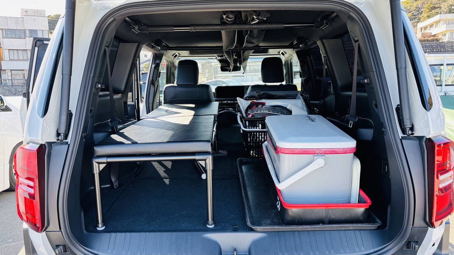 荷室の左側にマットを敷いたベッド、右側にクーラーボックスと釣り具を積んだランドクルーザー250の荷室