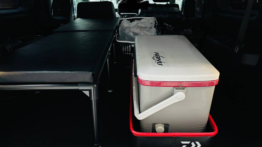 黒いマットのベッドの横にクーラーボックスを置いた荷室