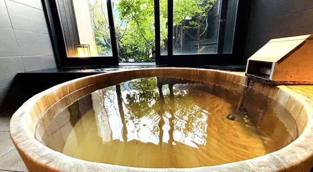 窓の外に緑が見える木の湯船